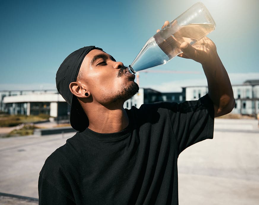 City heat, summer and urban young man drinking water.
